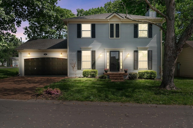 colonial inspired home featuring a yard, an attached garage, a chimney, and driveway