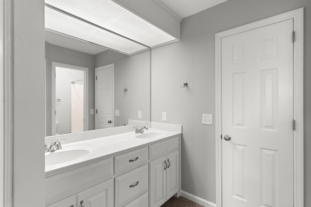 bathroom featuring a sink, baseboards, and double vanity