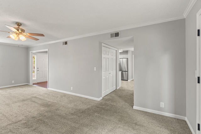 carpeted spare room featuring a ceiling fan, visible vents, and ornamental molding