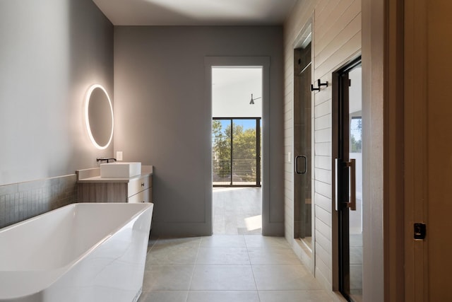 full bath with vanity, a stall shower, a freestanding bath, and tile patterned flooring