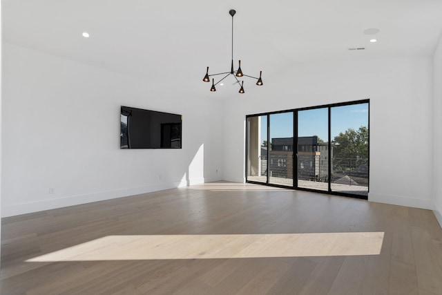 spare room with an inviting chandelier, recessed lighting, baseboards, and wood finished floors