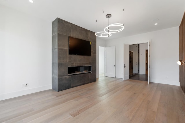 unfurnished living room with baseboards, a fireplace, and light wood-type flooring