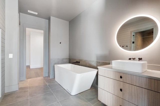 bathroom with vanity, tile patterned flooring, visible vents, tile walls, and a freestanding bath