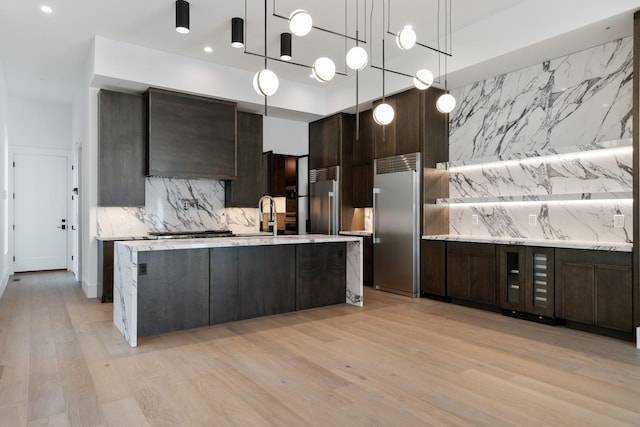 kitchen featuring high end refrigerator, backsplash, light wood-style flooring, and dark brown cabinets