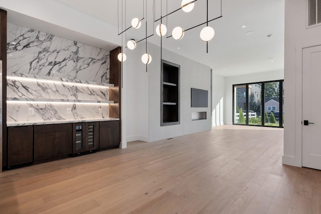 interior space featuring visible vents, light wood finished floors, hanging light fixtures, and built in shelves