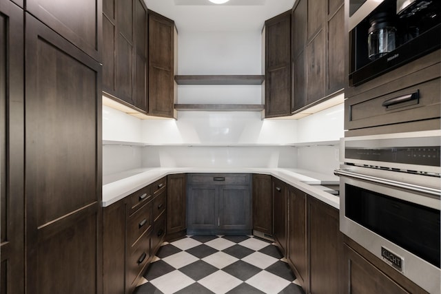 kitchen featuring oven, open shelves, dark brown cabinetry, light countertops, and light floors