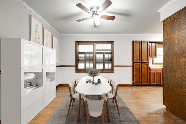 dining area featuring a ceiling fan, baseboards, ornamental molding, and light wood finished floors