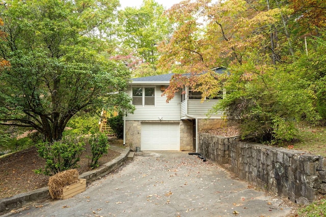 view of home's exterior featuring stone siding, roof with shingles, stairs, an attached garage, and driveway