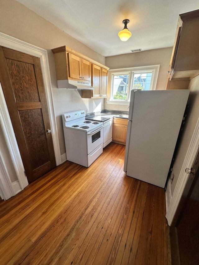 kitchen with white appliances, visible vents, a sink, and light wood-style floors