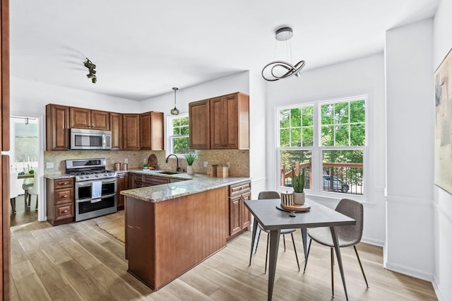 kitchen with a sink, appliances with stainless steel finishes, decorative backsplash, and a peninsula