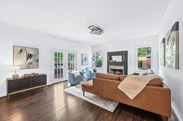 living area featuring plenty of natural light, a lit fireplace, dark wood-type flooring, and french doors