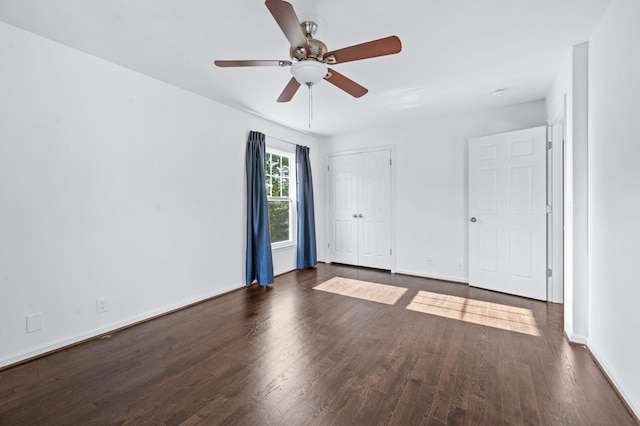 unfurnished bedroom with baseboards, ceiling fan, a closet, and dark wood-style flooring