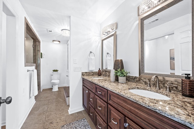 bathroom with double vanity, a sink, baseboards, and toilet