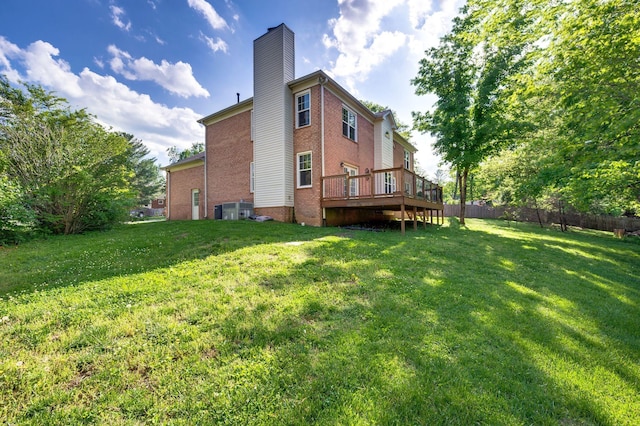 rear view of house with a lawn, fence, a chimney, and a deck