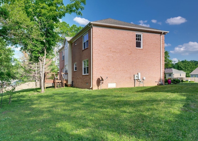 back of property with a lawn, a deck, and brick siding