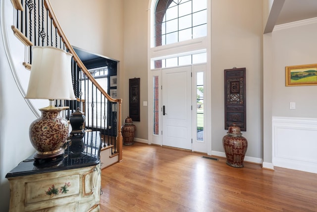 foyer featuring stairs, a high ceiling, visible vents, and light wood-type flooring