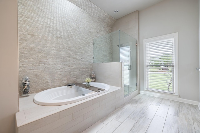 bathroom with baseboards, a stall shower, and a bath