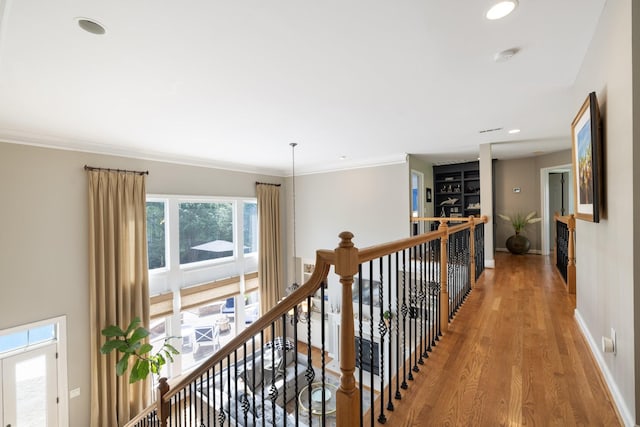 hall with crown molding, wood finished floors, baseboards, an upstairs landing, and recessed lighting