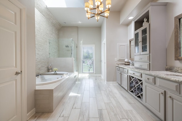 bathroom with vanity, baseboards, a bath, a shower stall, and a notable chandelier
