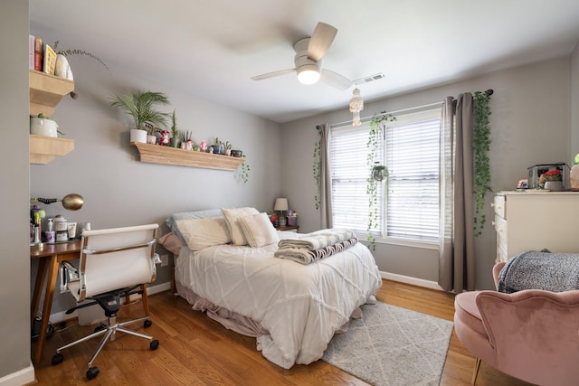 bedroom featuring ceiling fan, baseboards, visible vents, and wood finished floors