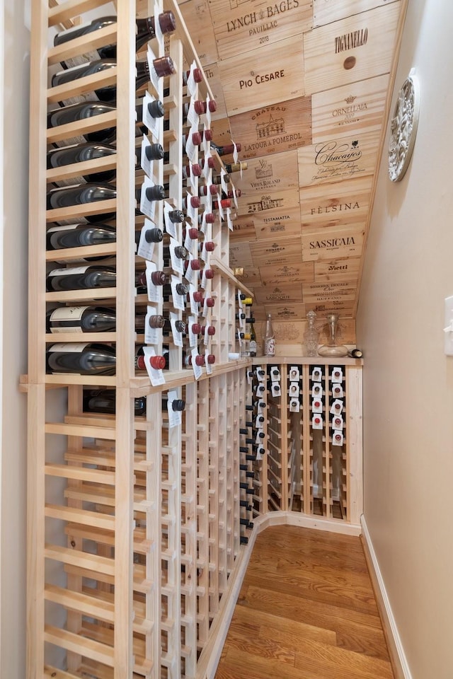 wine area with baseboards, wood ceiling, and wood finished floors