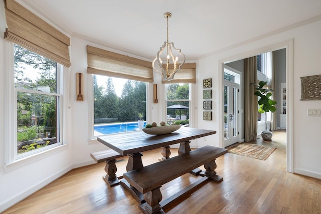 dining space featuring a healthy amount of sunlight, baseboards, light wood-type flooring, and a chandelier