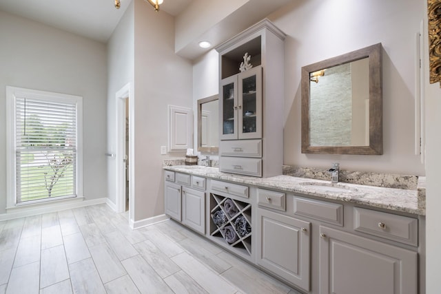 full bath featuring double vanity, baseboards, and a sink