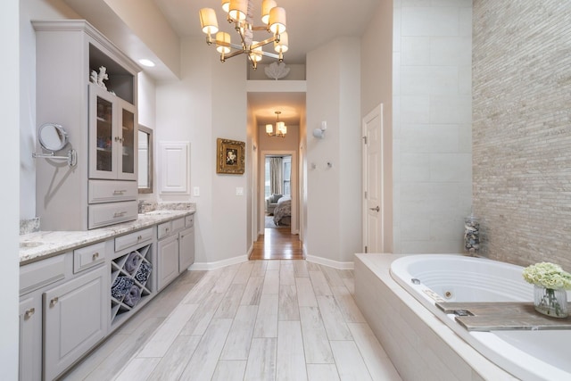 ensuite bathroom featuring an inviting chandelier, a whirlpool tub, ensuite bathroom, and vanity