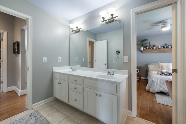 full bath featuring connected bathroom, double vanity, baseboards, and a sink