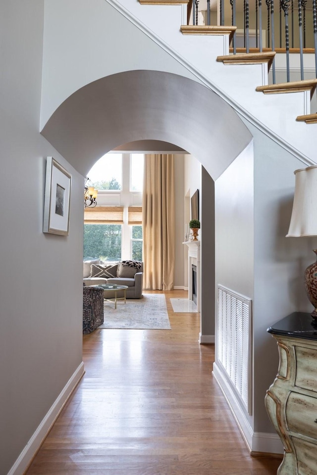 foyer entrance featuring arched walkways, baseboards, and wood finished floors