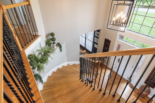 stairs with wood finished floors and a chandelier