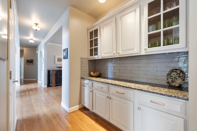 bar featuring light wood-style floors, baseboards, and tasteful backsplash