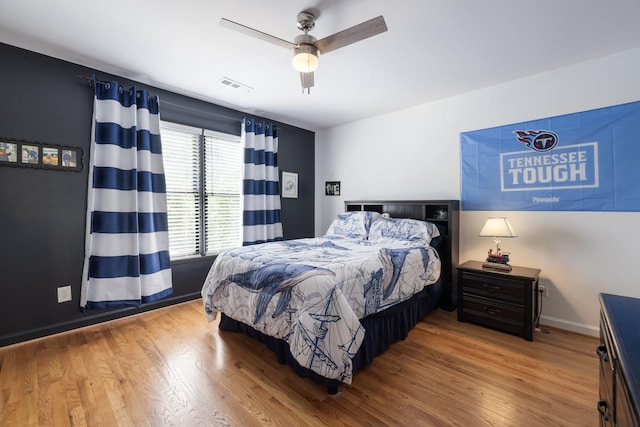 bedroom with baseboards, ceiling fan, wood finished floors, and visible vents