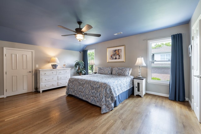 bedroom featuring a ceiling fan, baseboards, wood finished floors, vaulted ceiling, and visible vents