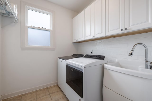 washroom with a sink, washer and clothes dryer, cabinet space, and baseboards