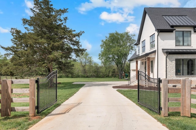 view of side of property with stone siding, a gate, a shingled roof, a fenced front yard, and a yard