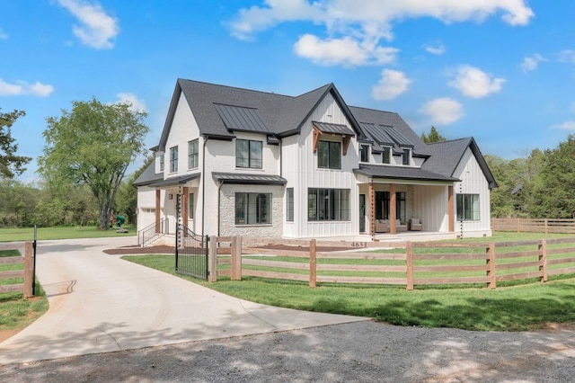 view of front of property with a standing seam roof, a fenced front yard, driveway, and metal roof