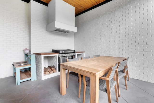 dining space with wooden ceiling, brick wall, and concrete floors