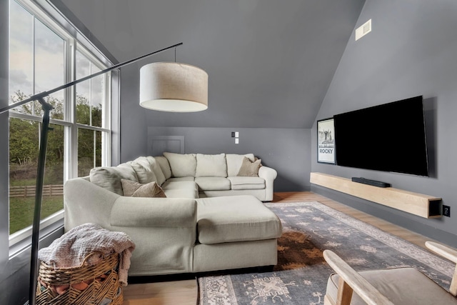 living room with visible vents, plenty of natural light, wood finished floors, and lofted ceiling
