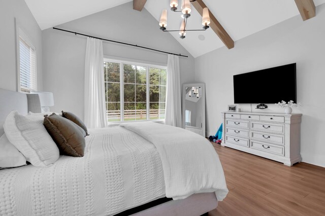 bedroom with a chandelier, lofted ceiling with beams, light wood-style flooring, and multiple windows