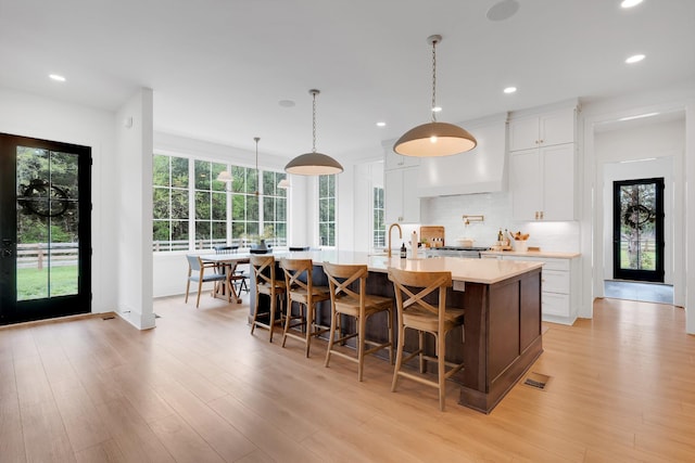 kitchen featuring recessed lighting, light countertops, premium range hood, and tasteful backsplash