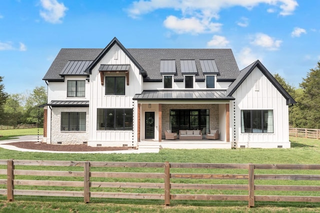 modern farmhouse with a standing seam roof, board and batten siding, a fenced front yard, and crawl space