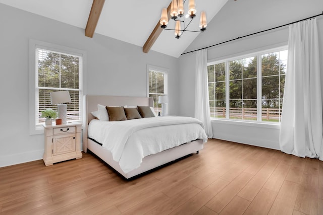 bedroom with an inviting chandelier, light wood-style flooring, multiple windows, and vaulted ceiling with beams