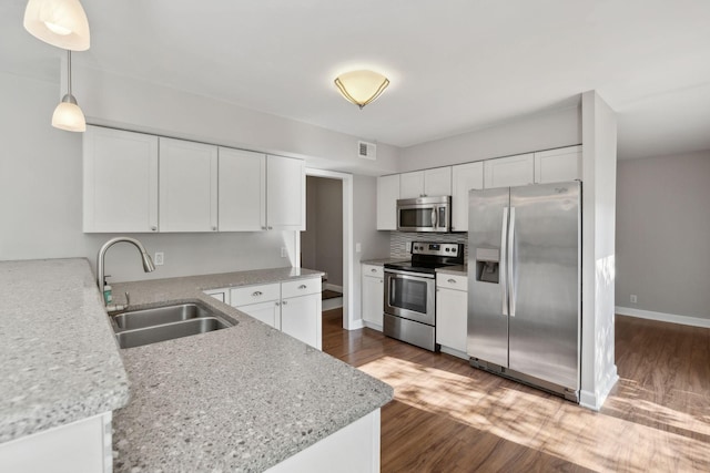 kitchen with visible vents, wood finished floors, a sink, stainless steel appliances, and white cabinetry