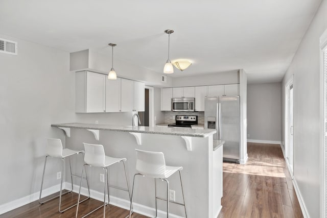 kitchen with visible vents, a peninsula, baseboards, white cabinets, and stainless steel appliances