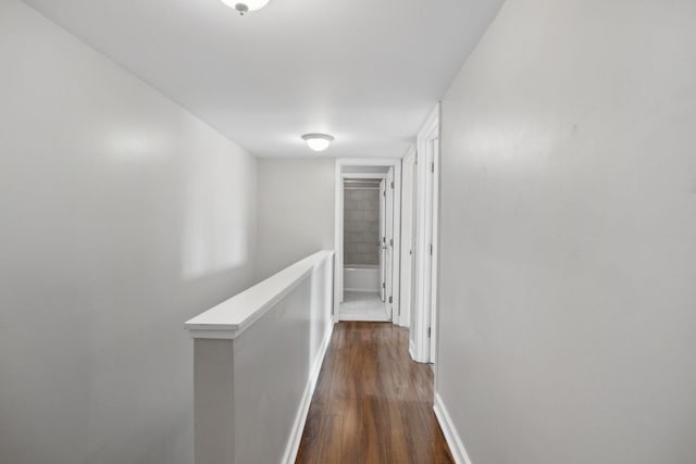 hallway featuring baseboards, dark wood finished floors, and an upstairs landing