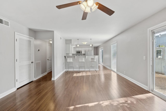 unfurnished living room with visible vents, baseboards, and wood finished floors