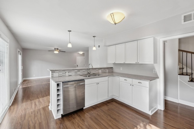 kitchen with a peninsula, white cabinets, a sink, dark wood finished floors, and dishwasher