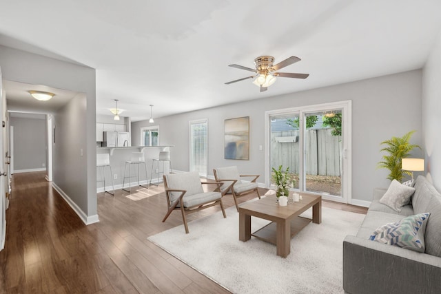 living room with baseboards, a ceiling fan, and wood finished floors