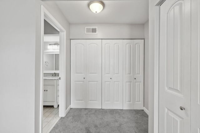 unfurnished bedroom with visible vents, a sink, a closet, connected bathroom, and light carpet